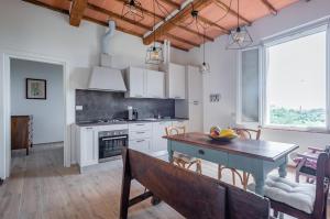 uma cozinha com armários brancos e uma mesa e cadeiras em Porta Romana Elegant House with Private Parking! em Siena