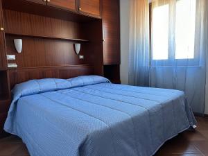 una camera da letto con un grande letto blu e una finestra di Hotel Alla città di Trieste a Grado