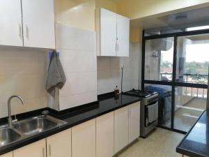 a kitchen with white cabinets and a sink at Serene apartment in the suburbs in Nairobi +3 photos