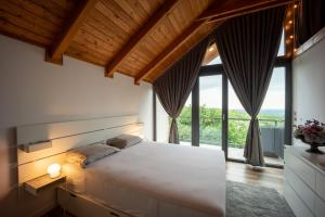 a bedroom with a large white bed and large windows at Copanjek Country House in Plešivica