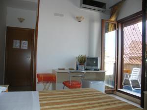 a bedroom with a bed and a desk with a television at Oasi del Sud in Pozzallo