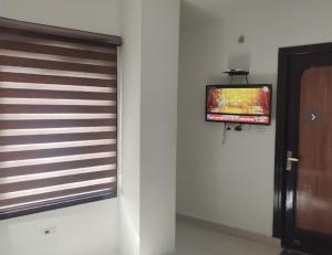 - une télévision murale dans une chambre avec une porte dans l'établissement Hotel Shivaahana Residency, Katra, à Katra