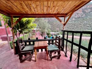 una mesa y sillas en un porche con techo de madera en Dar l'eau Vive, en Bine el Ouidane