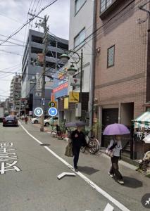 dos personas caminando por una calle con sombrillas en ホテルWakatsuki en Osaka