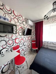 a room with a bedroom with a bed and red chairs at Sport Hotel Terra in Ustʼ-Kamenogorsk