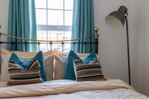 a bed with blue curtains and pillows on it at Cyrus House in Dartford