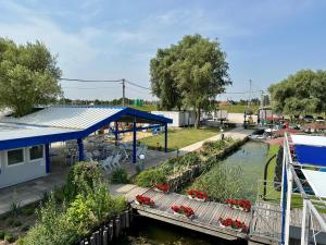 a marina with a building and a river with flowers at Tündérfátyol in Abádszalók