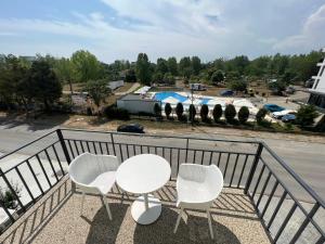 a balcony with a white table and three chairs at Oxygen Residence Neptun in Neptun
