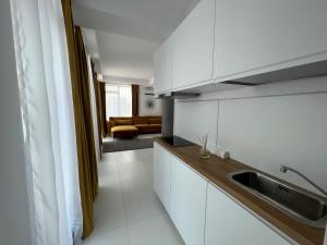 a kitchen with white cabinets and a sink at Oxygen Residence Neptun in Neptun