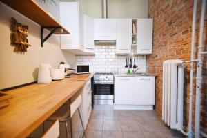 uma cozinha com armários brancos e uma parede de tijolos em Saltic Deluxe Apartment by 3City Rentals em Sopot