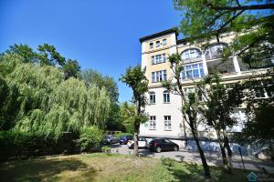 a white building with cars parked in a parking lot at Saltic Deluxe Apartment by 3City Rentals in Sopot