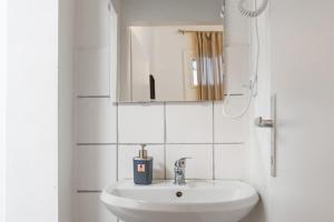 biała łazienka z umywalką i lustrem w obiekcie Affordable 2BR Apt- Connected to the whole city w Wiedniu