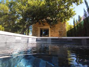 ein Wasserpool mit einem Gebäude im Hintergrund in der Unterkunft La perle de Gordes in Gordes