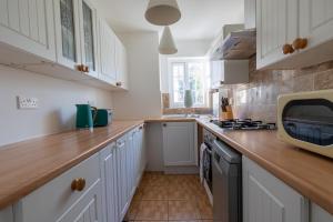 a kitchen with white cabinets and a wooden counter top at Cyrus House in Dartford