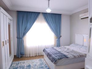 a bedroom with a large window with blue curtains at Royal Mansion with private pool in sheikh zayed Compound families in Sheikh Zayed