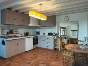 a kitchen with white cabinets and a table in it at Ancienne ferme Chessy in Chessy