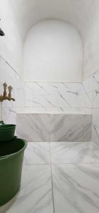 Baño de azulejos blancos con una planta en una maceta verde en Auberge Dar Laazouzi, 