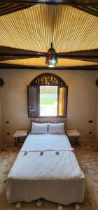 a bedroom with a large white bed with a window at Auberge Dar Laazouzi 