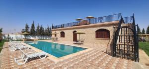 a swimming pool with lounge chairs next to a building at Auberge Dar Laazouzi in Sidi Mokhtar