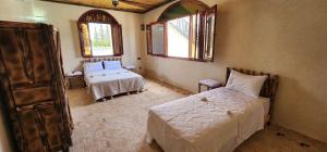 a bedroom with a bed and a couch and two windows at Auberge Dar Laazouzi 