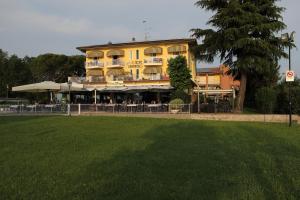 un gran edificio amarillo con césped delante en Hotel Campanello, en Castelnuovo del Garda