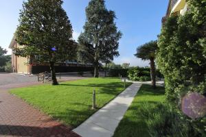 a park with green grass and trees and a sidewalk at Hotel Campanello in Castelnuovo del Garda