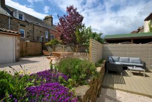 a garden with a couch and a table and flowers at Crows Neuk- fabulous coastal family home in Saint Monance