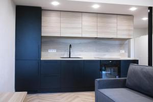 a kitchen with dark blue cabinets and a sink at Sniego Apartments in Vilnius