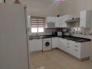 a kitchen with white cabinets and a washing machine at Villa Mimosa Tataouine in Tataouine