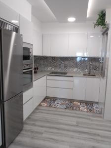 a kitchen with white cabinets and a tile floor at Aires do mar in O Grove