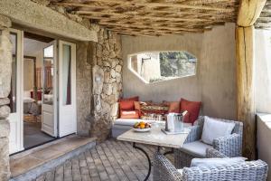 a patio with a table and chairs on a porch at Petra Segreta Resort & Spa in San Pantaleo