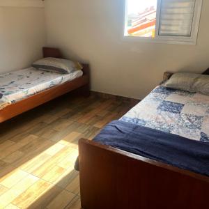 1 dormitorio con 2 camas y ventana en Catarina Chalé - Cond Clube en Mairinque