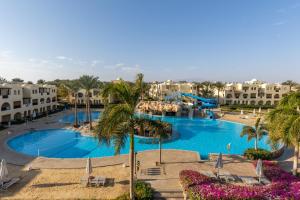 a view of a pool with palm trees and buildings at Stella Gardens Resort & Spa, Makadi Bay in Hurghada