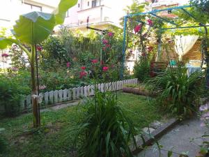 a garden with a white picket fence and flowers at Къща за Гости Тера in Kiten