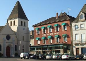 un edificio con una torre de reloj junto a un aparcamiento en Hôtel Les trois maures, en Verdun-sur-le-Doubs