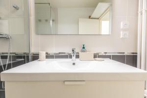 een witte badkamer met een wastafel en een spiegel bij *Cocoon Area* Confort & Parking in Clermont-Ferrand