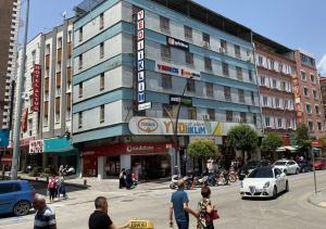 un grupo de personas cruzando una calle frente a un edificio en Hotel Altuğ, en Isparta