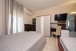 a hotel room with two beds and a desk and a table at Hotel Campanello in Castelnuovo del Garda