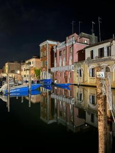 un groupe de bâtiments et de bateaux dans un canal la nuit dans l'établissement Casa Fiorenza, à Chioggia