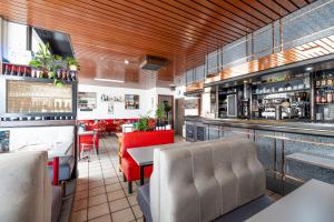 a restaurant with a bar with red chairs at Hotel De L'Agriculture - 2 étoiles in Saint-Hilaire-du-Harcouët