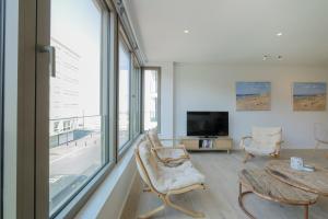 een woonkamer met een groot raam en een televisie bij Beautiful 3 bedrooms apartment 50 meters from the beach in Knokke-Heist