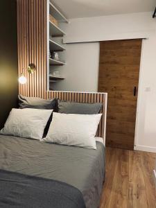 1 dormitorio con 1 cama con cabecero de madera en Lille Saint Maur, en La Madeleine
