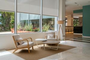 サロウにあるPonient Pirámide Salou by PortAventura Worldの椅子とテーブル、窓のあるロビー