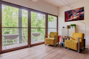 een woonkamer met 2 stoelen en een groot raam bij Dupre Cosy Residence in Brussel
