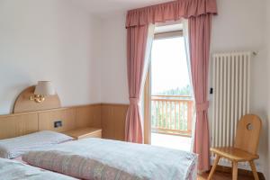 a bedroom with a bed and a window with a balcony at Tobià Brujà in Vigo di Fassa