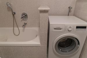 a bathroom with a washing machine next to a bath tub at Tobià Brujà in Vigo di Fassa