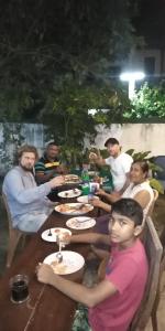 un grupo de personas sentadas en una mesa comiendo comida en Pearl Resort Mirissa en Mirissa