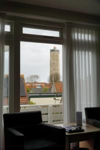 - un salon avec une fenêtre donnant sur un phare dans l'établissement Hotel Oepkes, à West-Terschelling