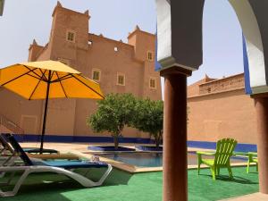 un patio con sillas, una sombrilla y una piscina en Kasbah ben hamou, en Nkob