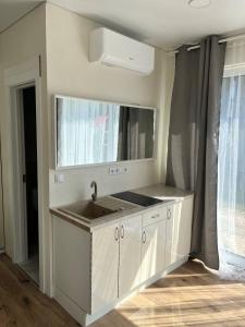 a white kitchen with a sink and a mirror at 4rest in Palanga